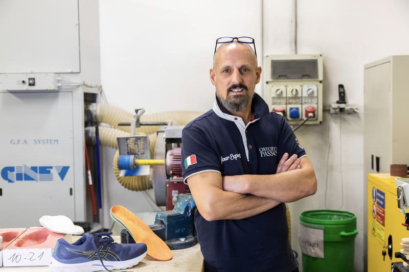 Un uomo con maglietta blu in officina - membro dello staff di un negozio di ortopedia a Pavia.